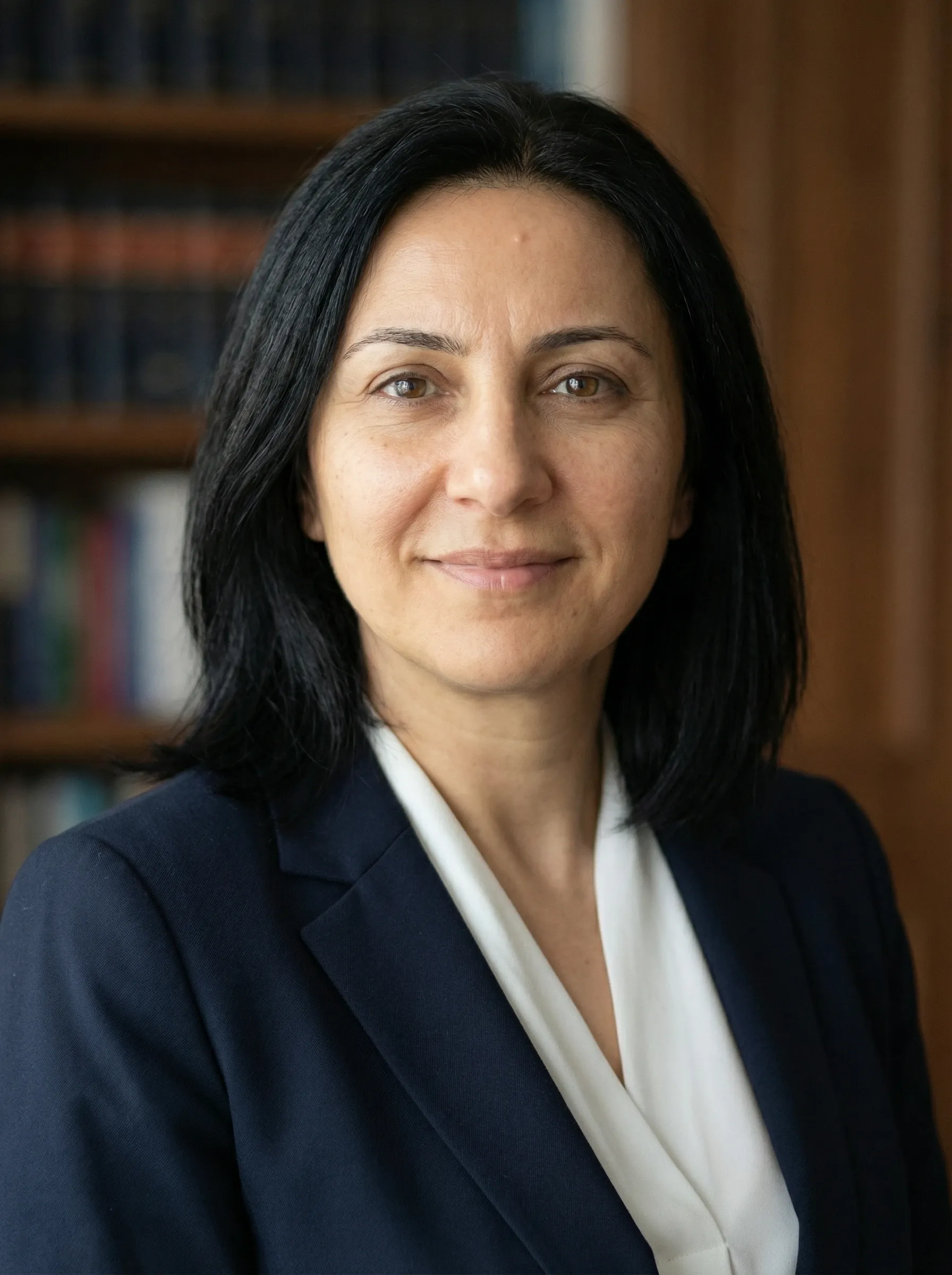 AI attorney headshot — woman in a navy blazer and white blouse with bookcases behind her